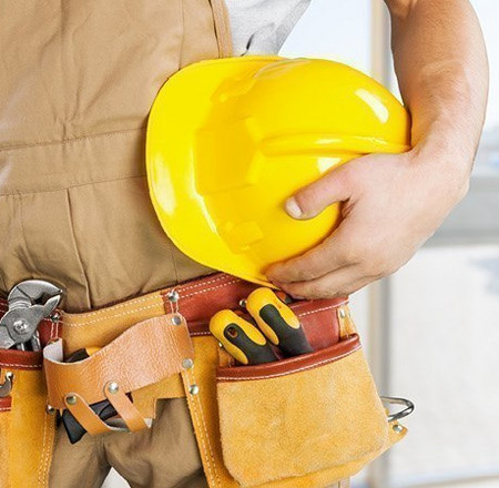 Handwerker mit gelbem Schutzhelm und Werkzeuggürtel, bereit für den Einsatz auf der Baustelle.