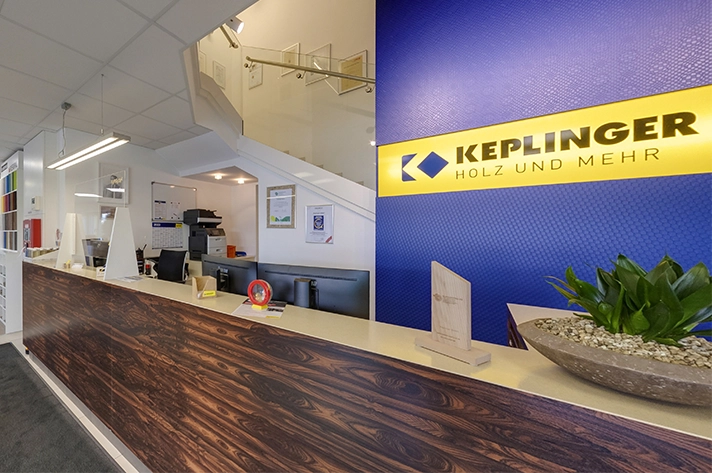 Empfangsbereich bei Keplinger Holz und Mehr mit moderner Einrichtung und Firmenlogo an der Wand.