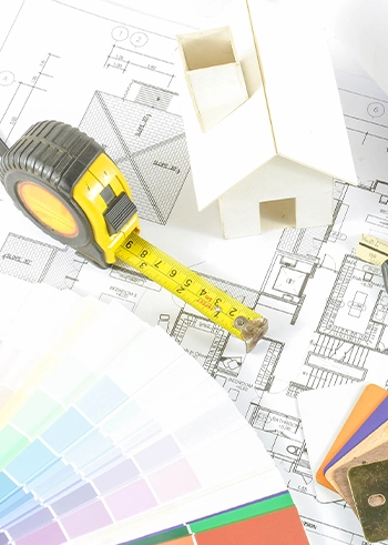 Architekturpläne mit Maßband, Farbfächern und Modellhaus – symbolisch für individuelle Planung.
